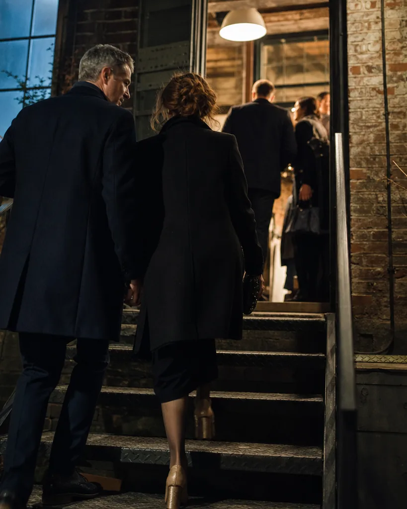Couple in their forties arriving at a private loft party up an industrial staircase in New York